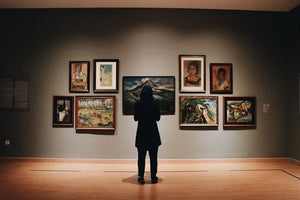A person looks at a wall of paintings in an art gallery | Visual impression for the page featuring all of Kunstiek's art collections.