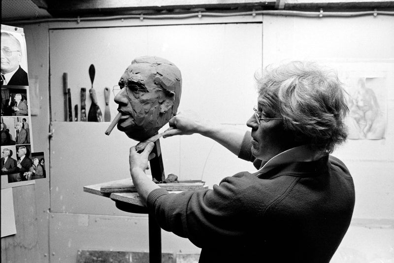 Kees Verkade | bezig met een sculptuur | een buste van Cees de Boer met een sigaar in zijn mond | in zijn atelier 1986