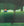 Dolf Zwerver, Orchard (1968), oil painting depicting a seated man wearing a red cap in a green orchard surrounded by tall hedges and trees, with two wooden ladders.