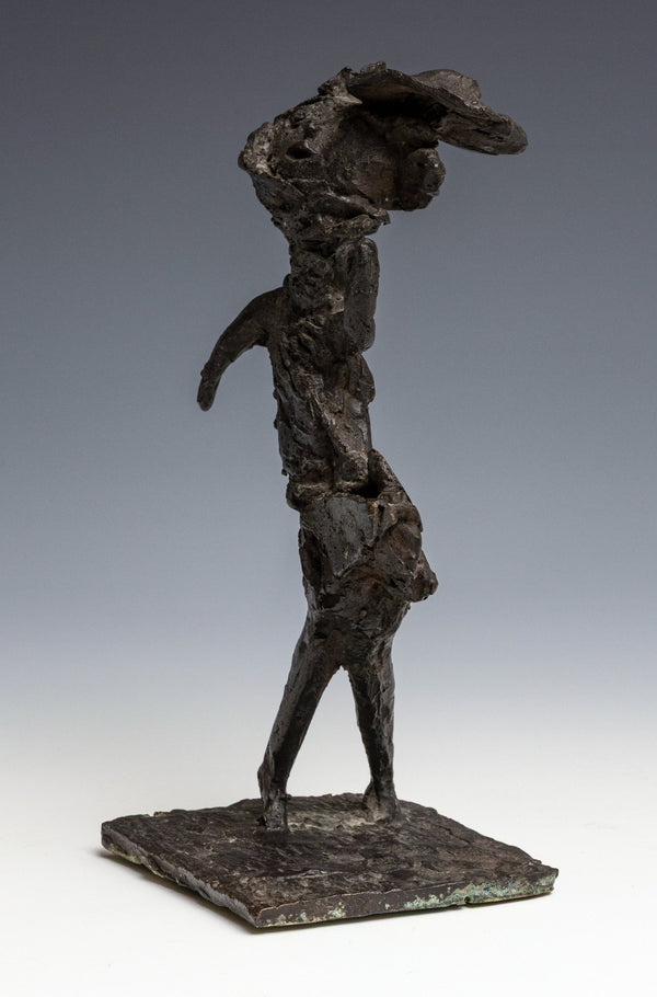 Dark patinated bronze, abstracted image of a lady in a dress with a hat who is caught in the wind. sideways